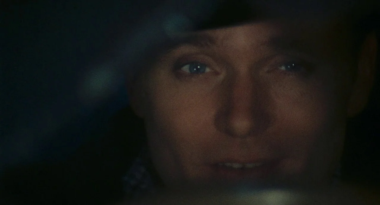 The Damned (1969) movie still: closeup — A dark vehicle interior at night with minimal illumination on the driver's face. The subject gazes forward…