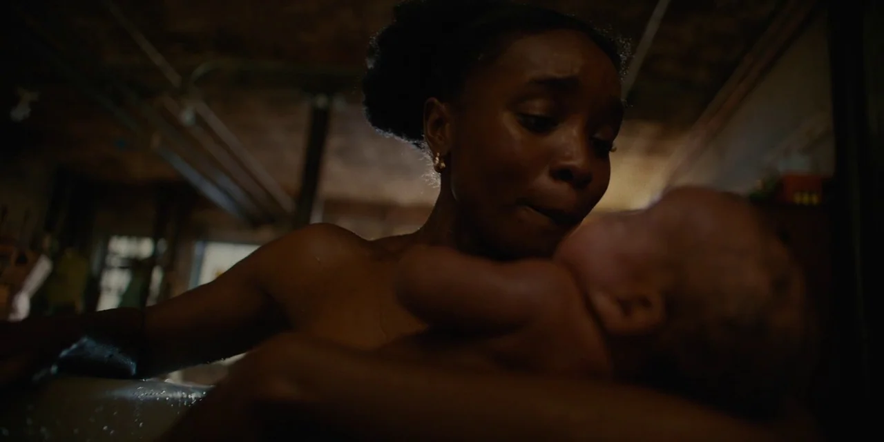 If Beale Street Could Talk (2018) movie still: medium — A dimly lit room with pipes visible on the ceiling in the background. A woman leans over a…