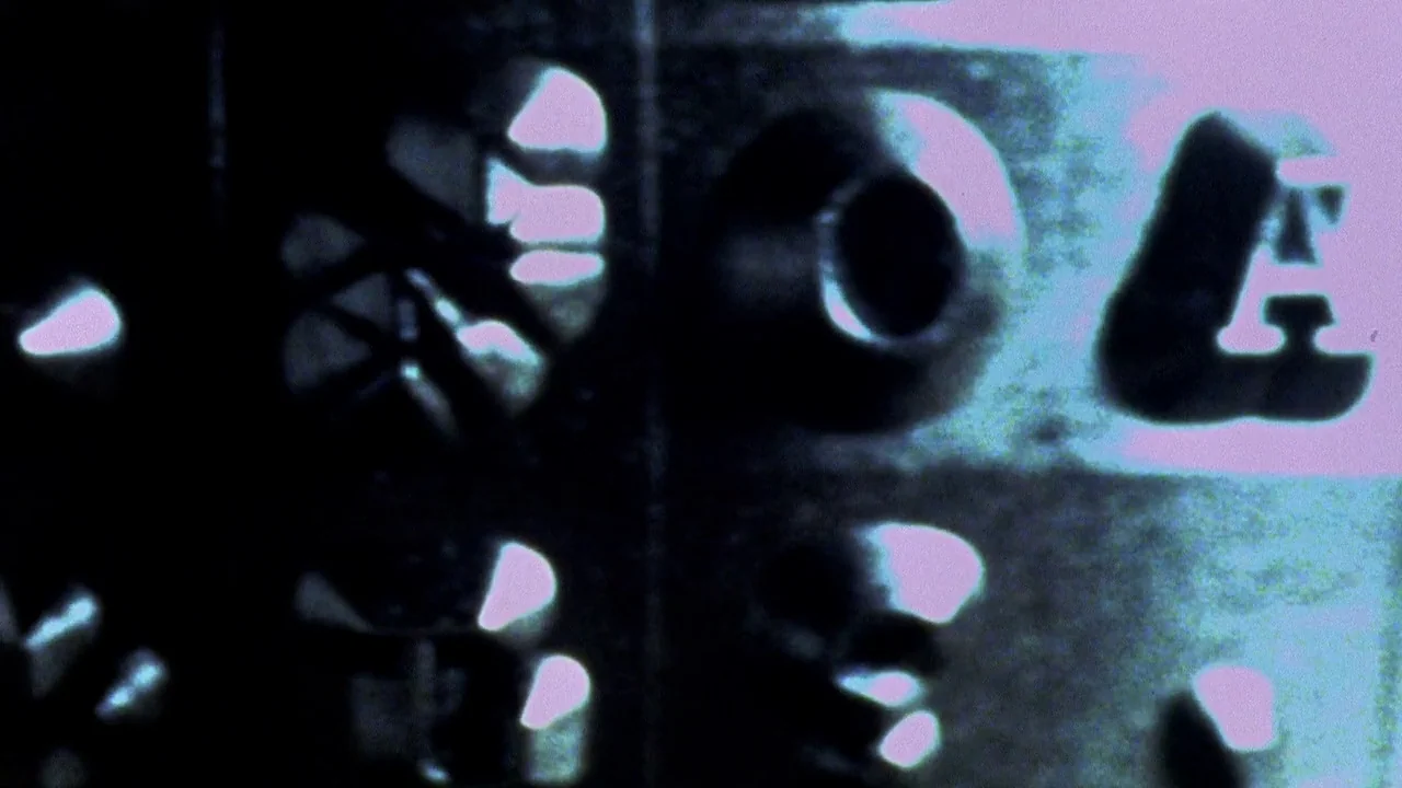 Secretary movie still: closeup — Abstract shapes and letters are visible in a high-contrast black and blue environment. The scene consists entirely…