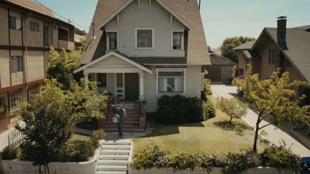Furious 7 (2015) movie still: wide — A suburban residential street features a two-story home with a white porch. A man walks down the stairs…