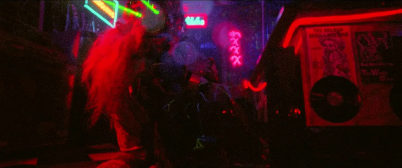 Christmas Bloody Christmas (2022) movie still: medium — A dark space features vibrant red and green neon signage on walls and machines. A person…
