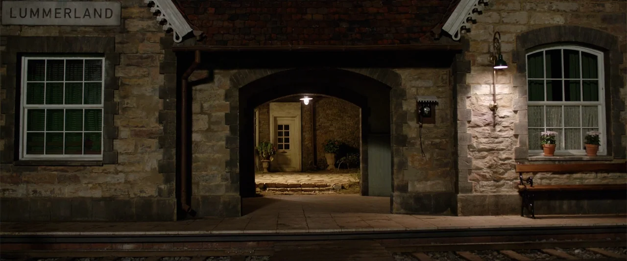 Jim Button and Luke the Engine Driver (2018) movie still: establishing — A stone train station at night features a sign labeled Lummerland and an…