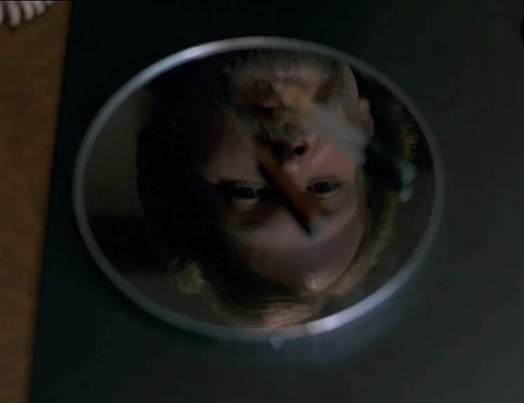 The Brother From Another Planet (1984) movie still: closeup — A man's face is seen reflected in a circular vanity mirror. The perspective is…