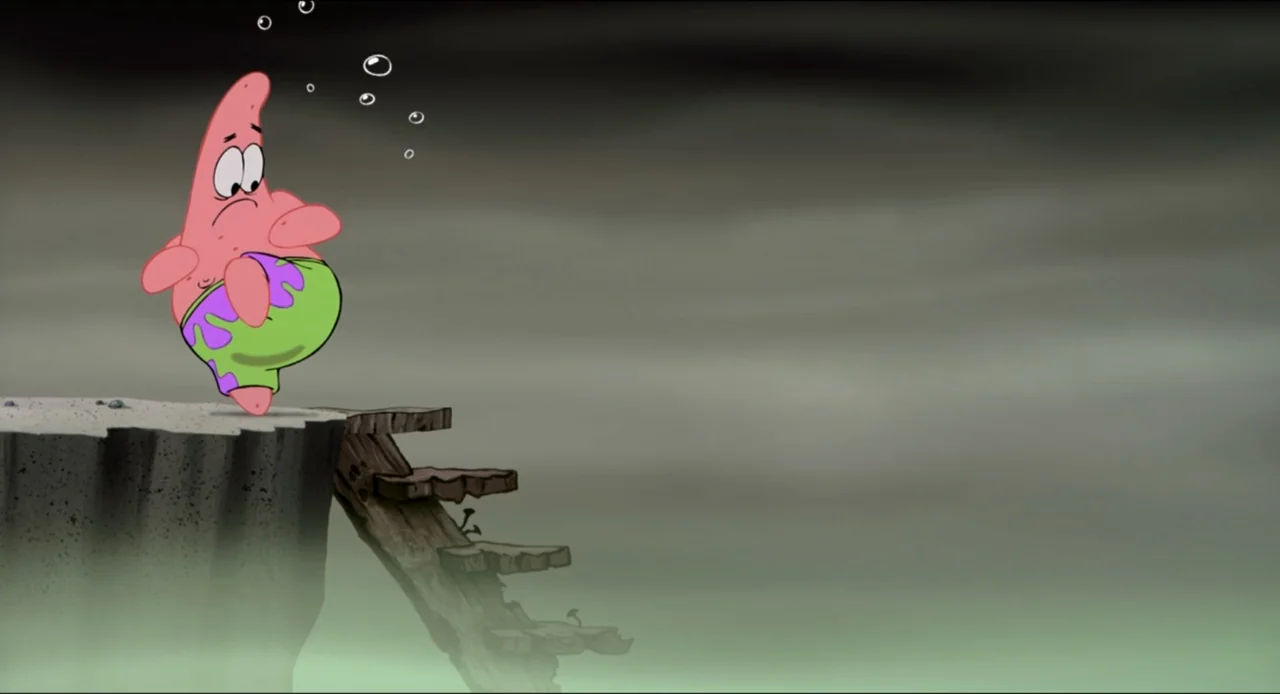 The SpongeBob SquarePants Movie (2004) movie still: medium — A pink cartoon starfish character stands on the edge of a rocky cliff ledge. The…