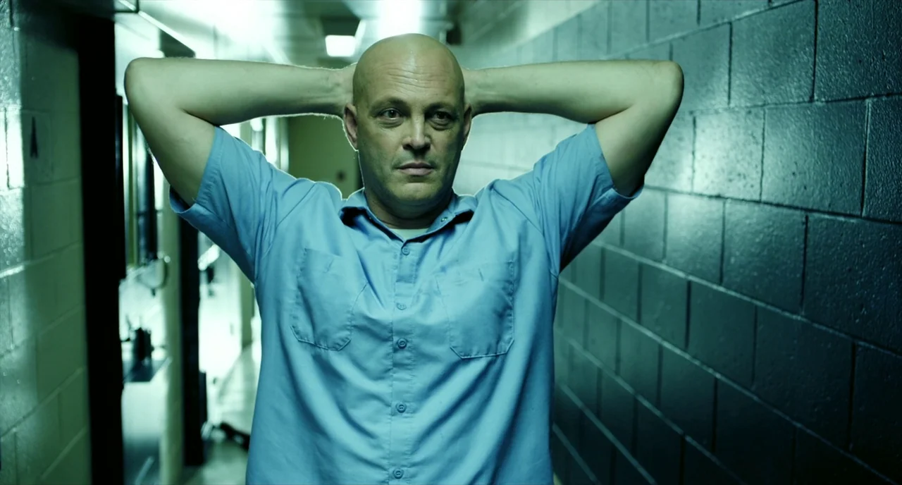 Brawl in Cell Block 99 (2017) movie still: medium — A narrow corridor features dark painted concrete block walls and overhead industrial lighting. A…