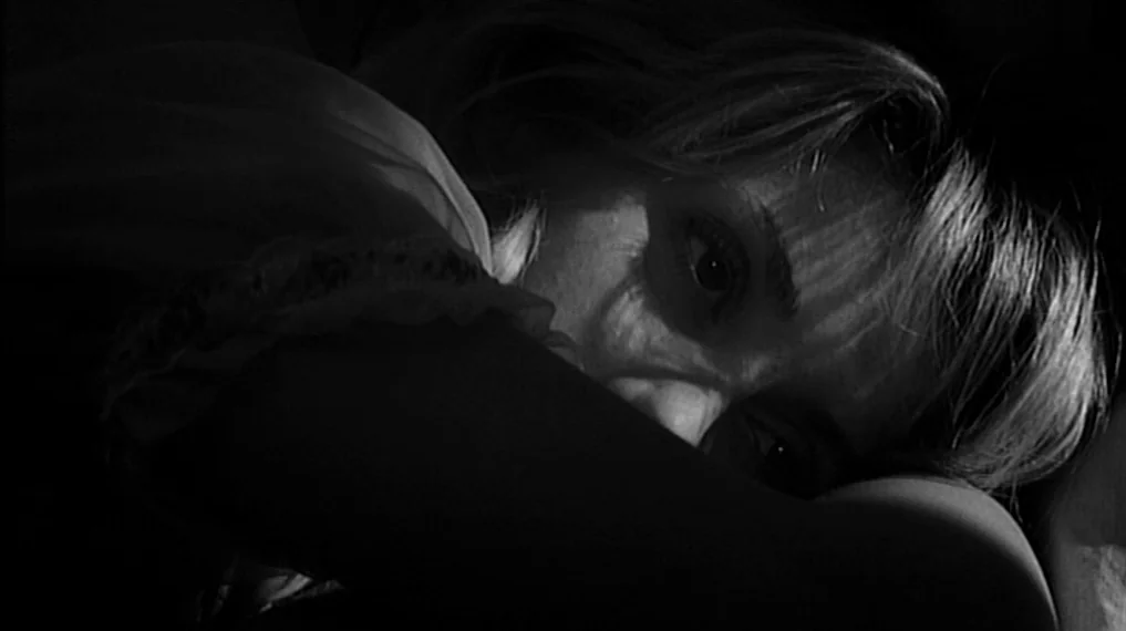 Repulsion (1965) movie still: closeup — A dark, low-key interior scene highlights the subject against a pitch-black background. A woman's face is…