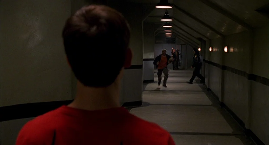 Spider-Man (2002) movie still: medium — An underground industrial passage features beige walls, concrete flooring, and repetitive overhead light…