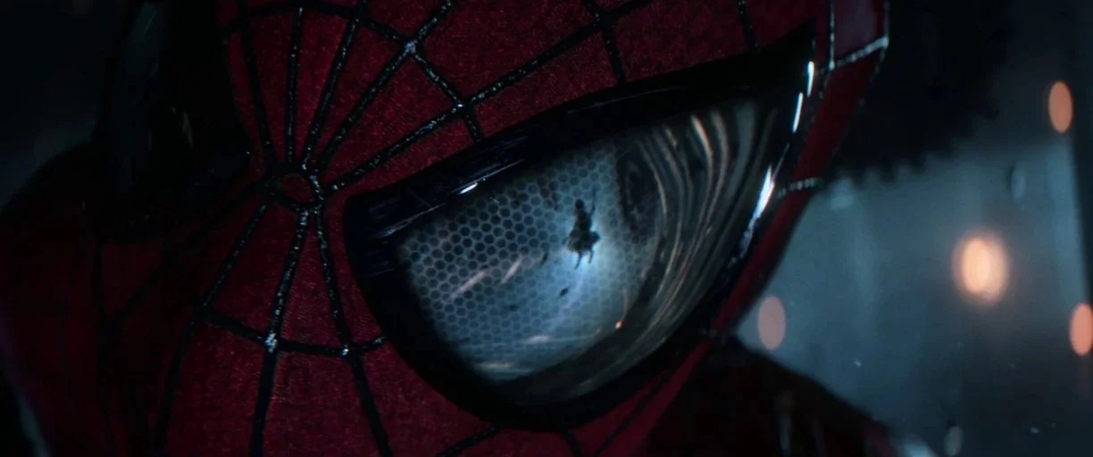 The Amazing Spider-Man (2012) movie still: closeup — The extreme close-up focuses on a red mask lens with a reflection inside. A tiny human…