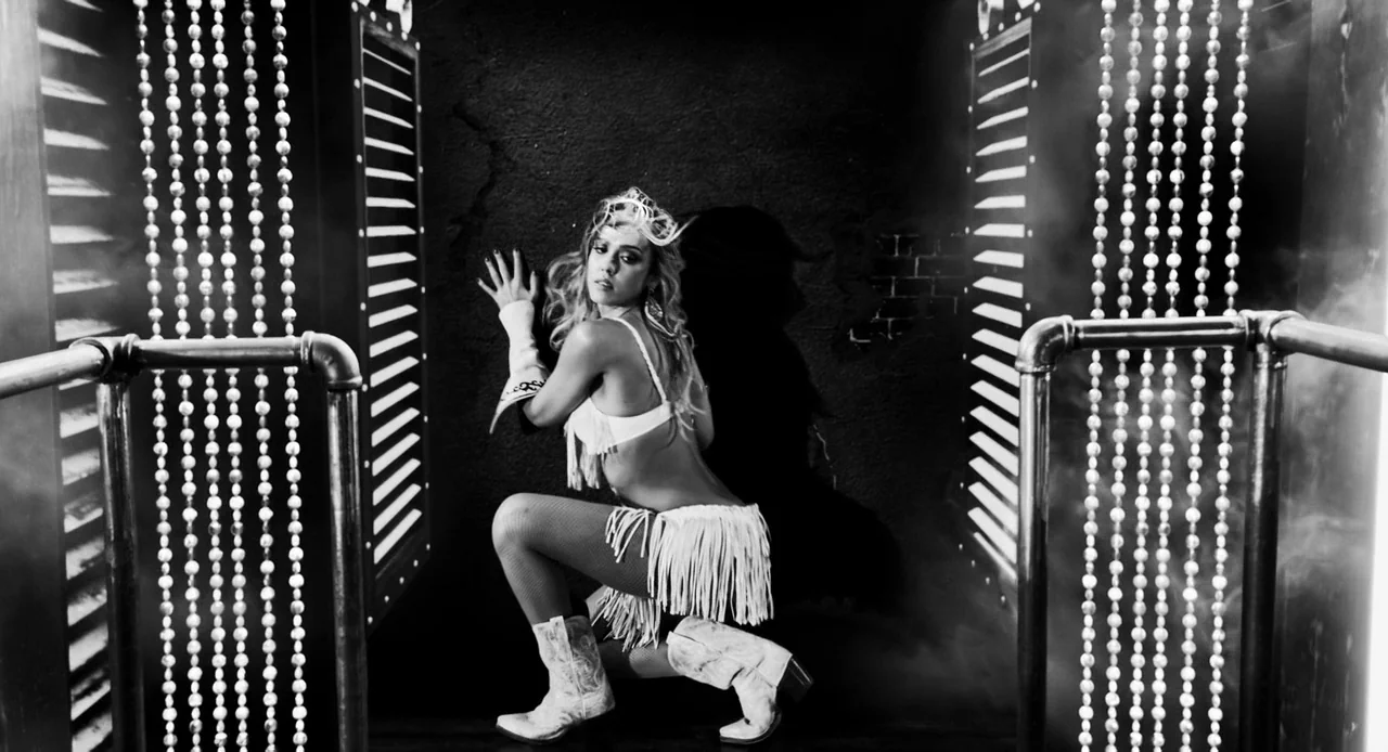 Sin City: A Dame to Kill For (2014) movie still: medium — A dark performance area featuring beaded curtains flanking a textured black wall. A woman…