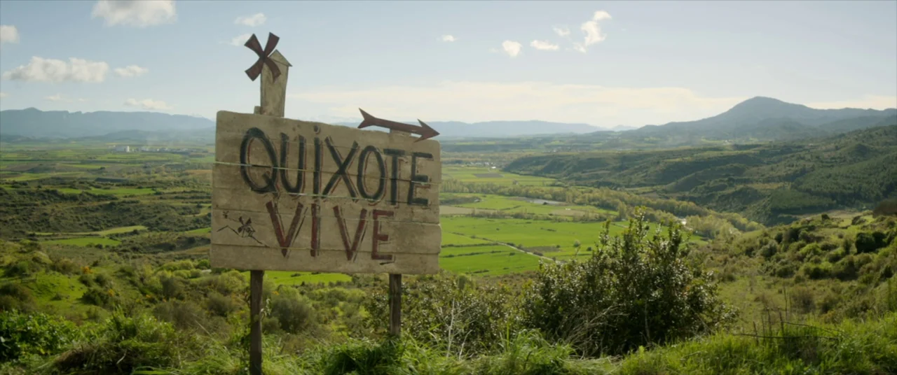 The Man Who Killed Don Quixote (2018) movie still: establishing — A rural valley features green hills and pastures stretching toward distant…
