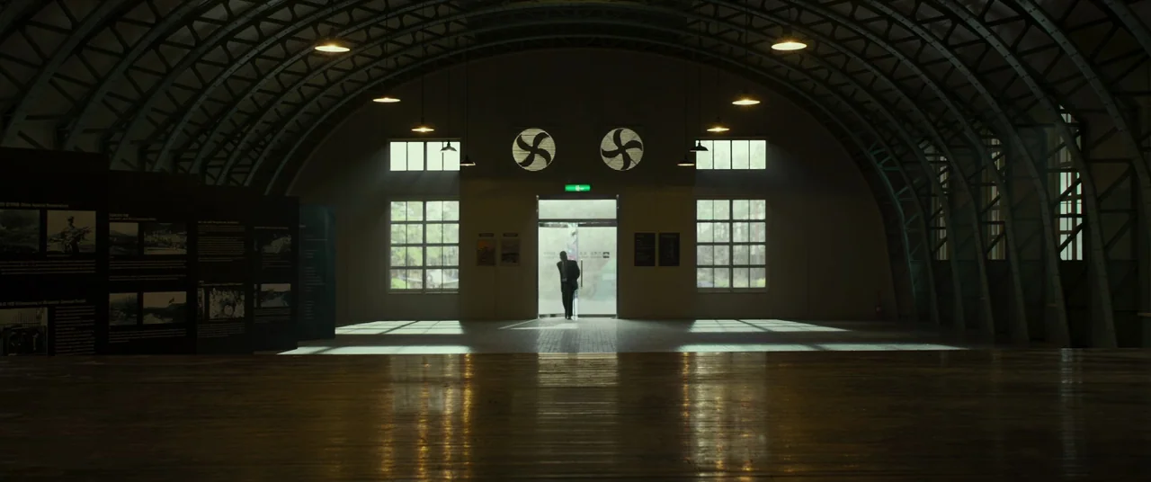 Swing Kids (2018) movie still: wide — A large hangar-style building with high arched ceilings and a polished wooden floor. A single man enters…