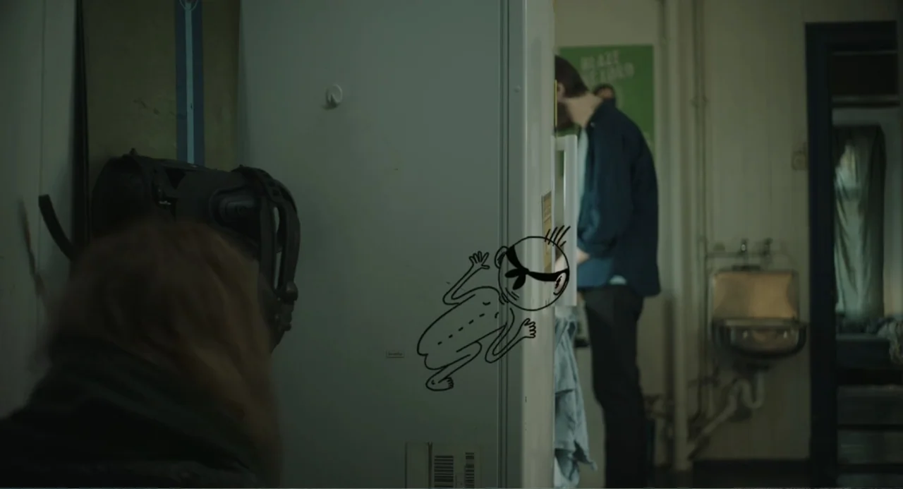 Ninjababy (2021) movie still: medium — A dimly lit kitchen features a white refrigerator adorned with a hand-drawn cartoon character. A man stands…