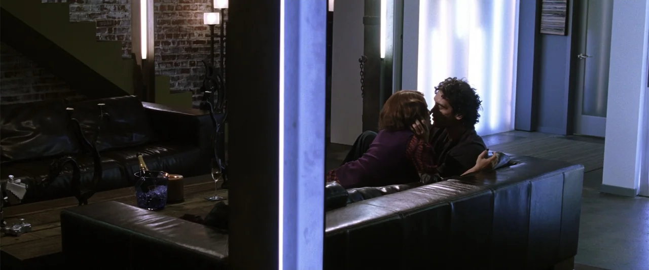 He's Just Not That Into You (2009) movie still: medium — A modern living area features an exposed brick wall and a black leather sofa. A man and a…