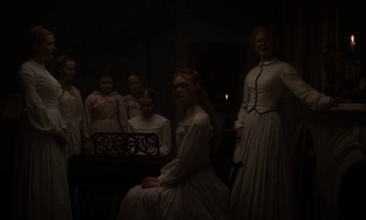 The Beguiled (2017) (2017) movie still: wide — A dark Victorian parlor is illuminated only by the faint light of a single candle. Six women in long…