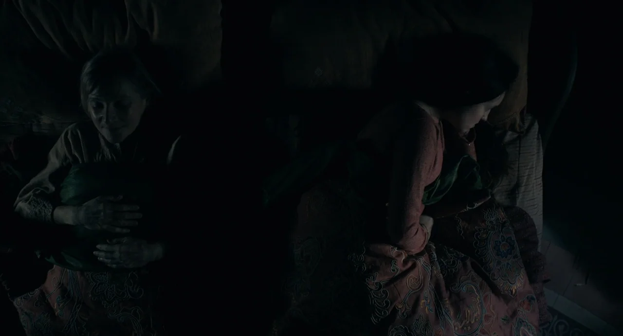 Catherine Called Birdy (2022) movie still: medium — An interior bedroom at night with two women sleeping in a bed. The figures lie side by side…