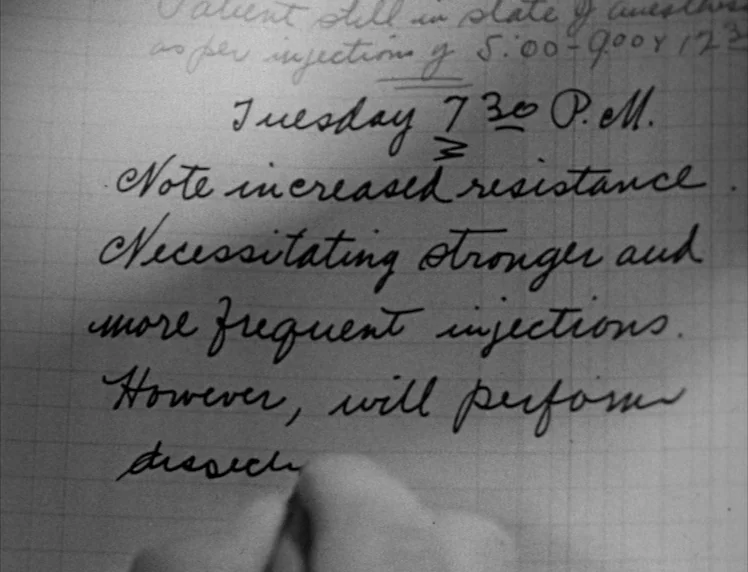 Frankenstein movie still: closeup — A close-up of a hand-written medical journal entry on grid-lined paper. The text details patient injection times…