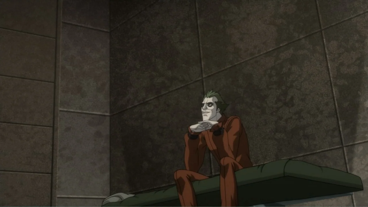 Batman: Assault on Arkham (2014) movie still: medium — A spartan room features dark, slab-like walls and a flat cushioned bench. A male figure with…