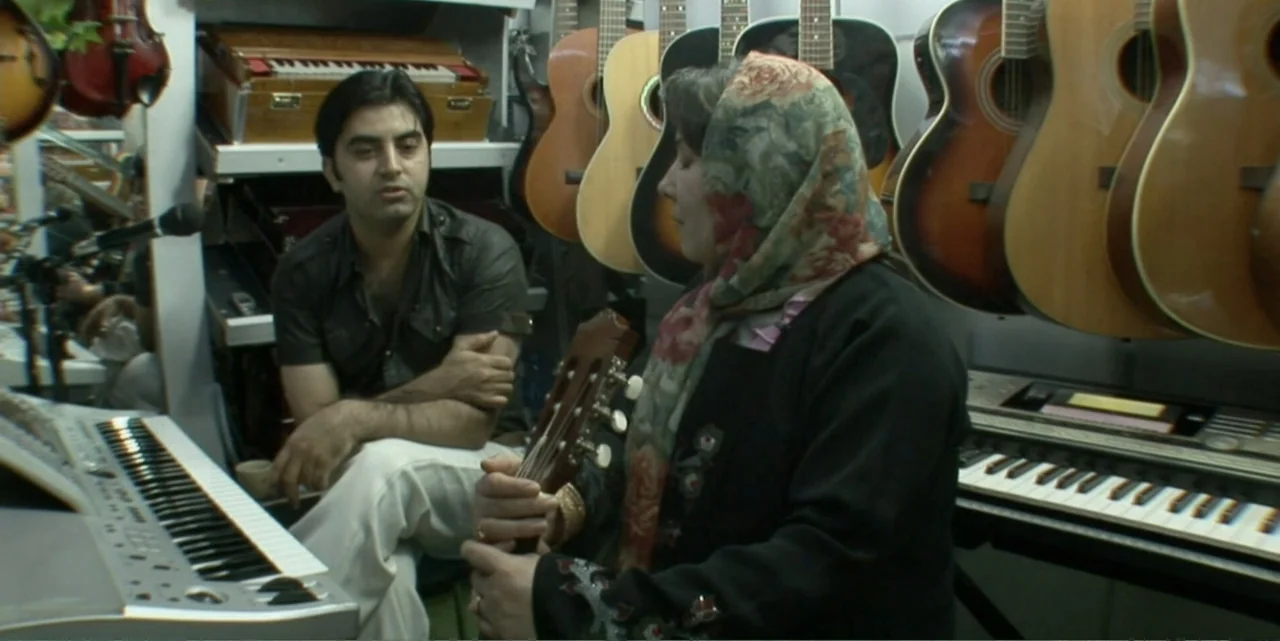 Silencing the Song: An Afghan Fallen Star (2011) movie still: medium — A cluttered music shop is filled with various acoustic guitars hung on the…