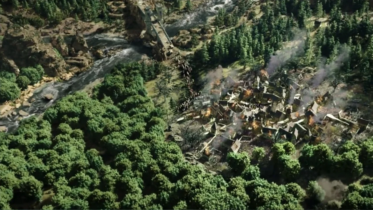 Warcraft (2016) movie still: establishing — A dense forest borders a small medieval village with several buildings engulfed in flames. A large army…