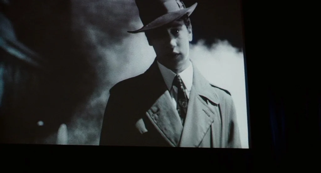 It’s Kind Of A Funny Story (2010) movie still: medium — A night scene on a city street obscured by thick clouds of dark smoke. A man in a trench…