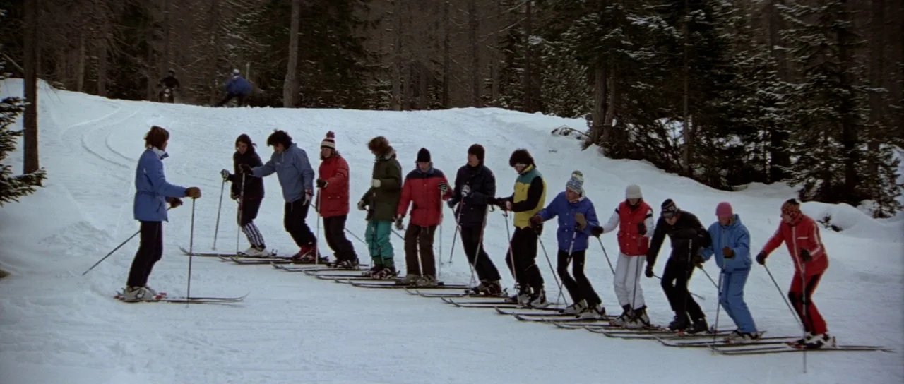 For Your Eyes Only (1981) movie still: wide — A group of twelve skiers stands in a staggered line across a snow-covered incline. Bare pine trees…