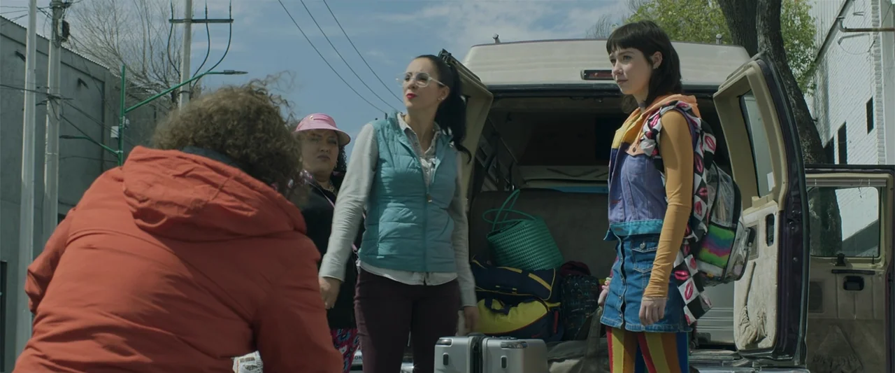 Mirreyes contra Godínez 2: El retiro (2022) movie still: fullbody — A group of women stands around the open rear doors of a white van. The vehicle…