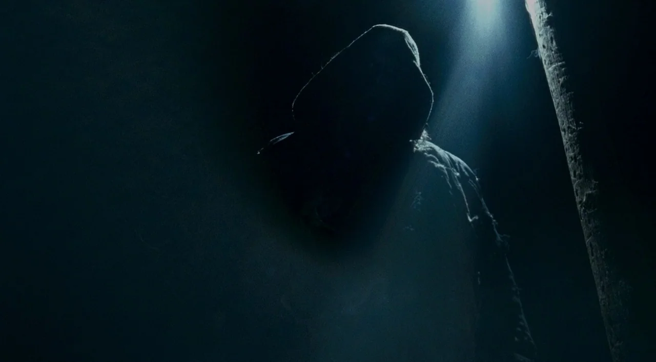 Halloween 2 (2009) movie still: medium — A dark outdoor space at night with a single bright overhead light fixture. A shrouded figure stands in the…