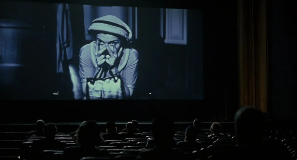 Far From Heaven (2002) movie still: wide — A dark, empty-looking movie theater viewed from the back of the auditorium seating area. A black and…