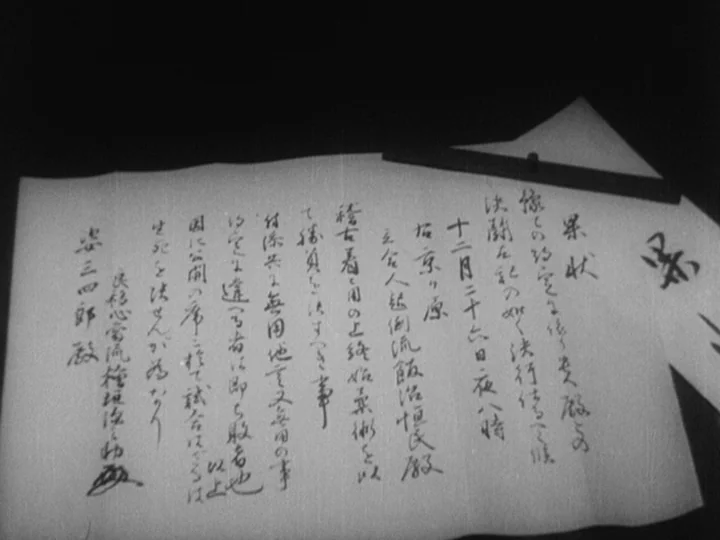 Sanshiro Sugata (1943) movie still: closeup — A handwritten document sits on a dark wooden surface in black and white. The paper contains Japanese…