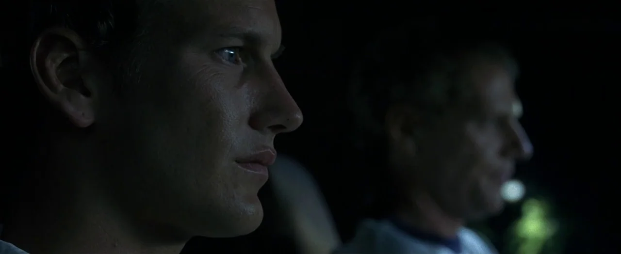 Little Children (2006) movie still: closeup — Two men sit in a dark car interior at night. The man in the foreground is in profile.