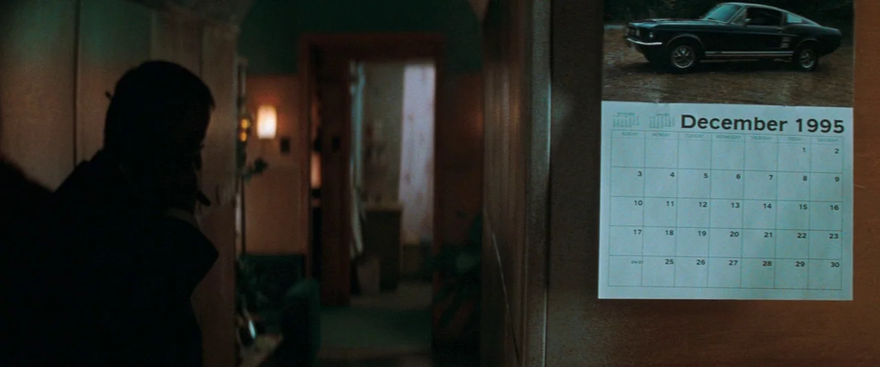 The Sweet Hereafter (1997) movie still: medium — A dimly lit indoor passage features a wall calendar prominently displayed on the side. A dark…