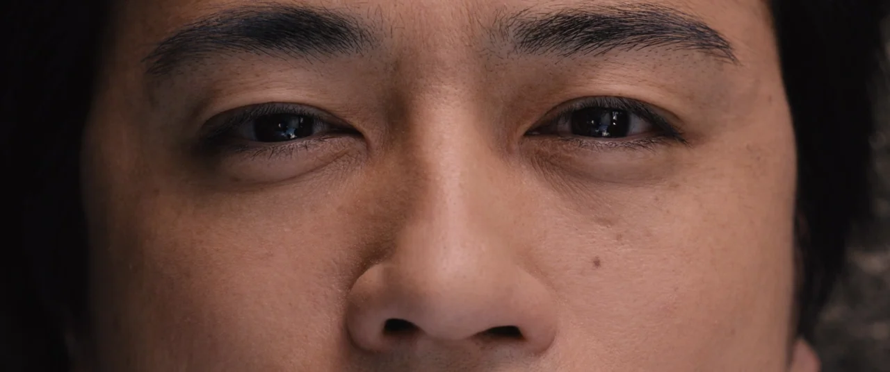 Shin Ultraman (2022) movie still: closeup — An extreme close-up of a man's eyes and nose. The subject looks directly into the camera lens from a…