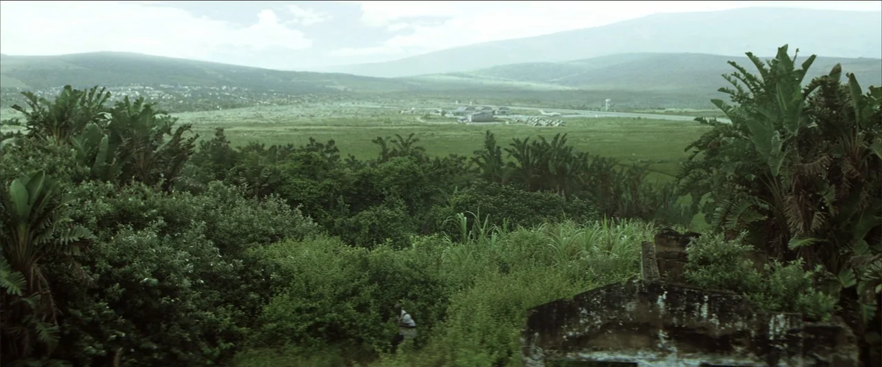 Blood Diamond (2006) movie still: establishing — A vast green valley extends toward distant mountains under a hazy light-filled sky. Dense tropical…