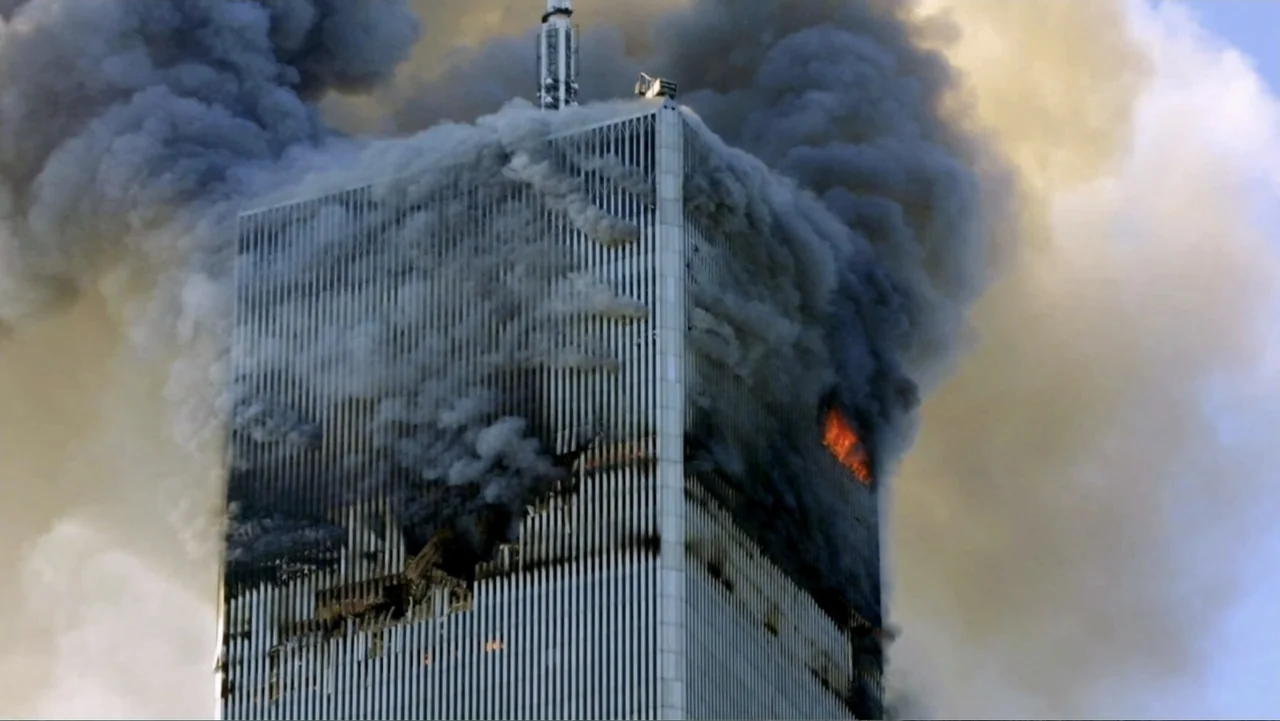 In the Shadow of the Towers: Stuyvesant High on 9/11 (2019) movie still: wide — A damaged skyscraper stands against a clear sky while thick black…