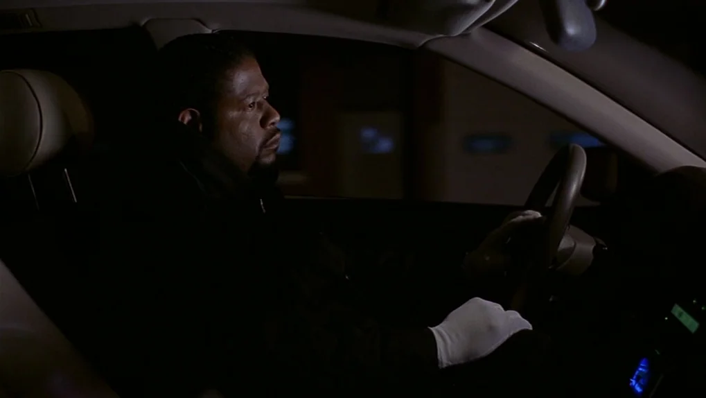Ghost Dog: The Way of the Samurai (1999) movie still: medium — The interior of a late-model car at night is dimly lit by external lights. A man with…