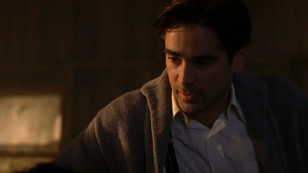 Ask The Dust (2006) movie still: medium — A dimly lit indoor space with shadows obscuring most of the surrounding wall texture. A man wearing a knit…