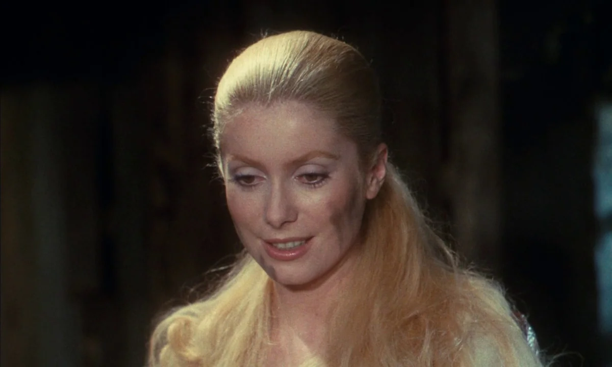 Donkey Skin (1970) movie still: closeup — A dimly lit room provides a dark background for the close-up portrait. The subject looks downward with a…