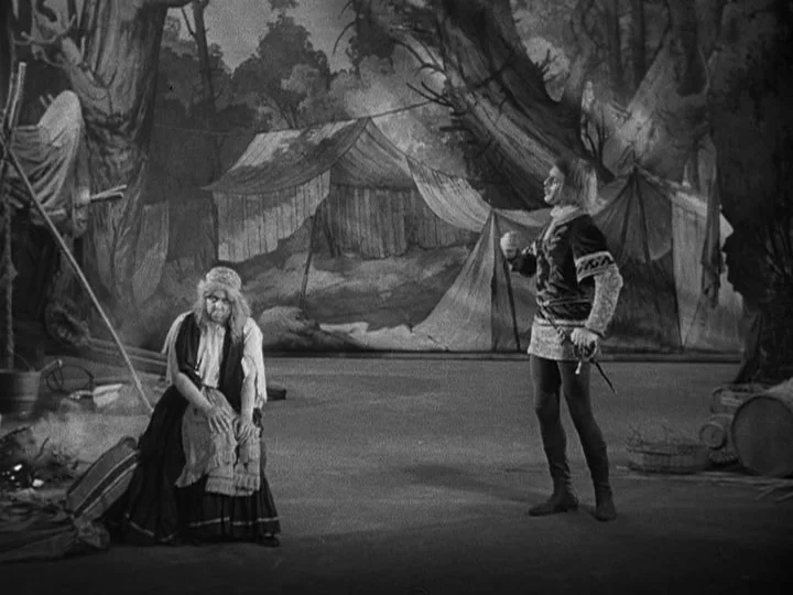 A Night at the Opera (1935) movie still: wide — A theatrical stage set features a painted backdrop of tents and forest. A woman sits on the floor…