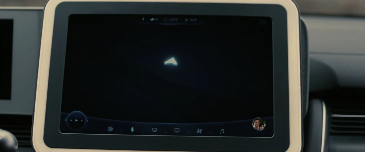 Companion (2025) movie still: closeup — A vehicle dashboard screen shows a minimalist navigation interface with a single arrow icon. The screen is…