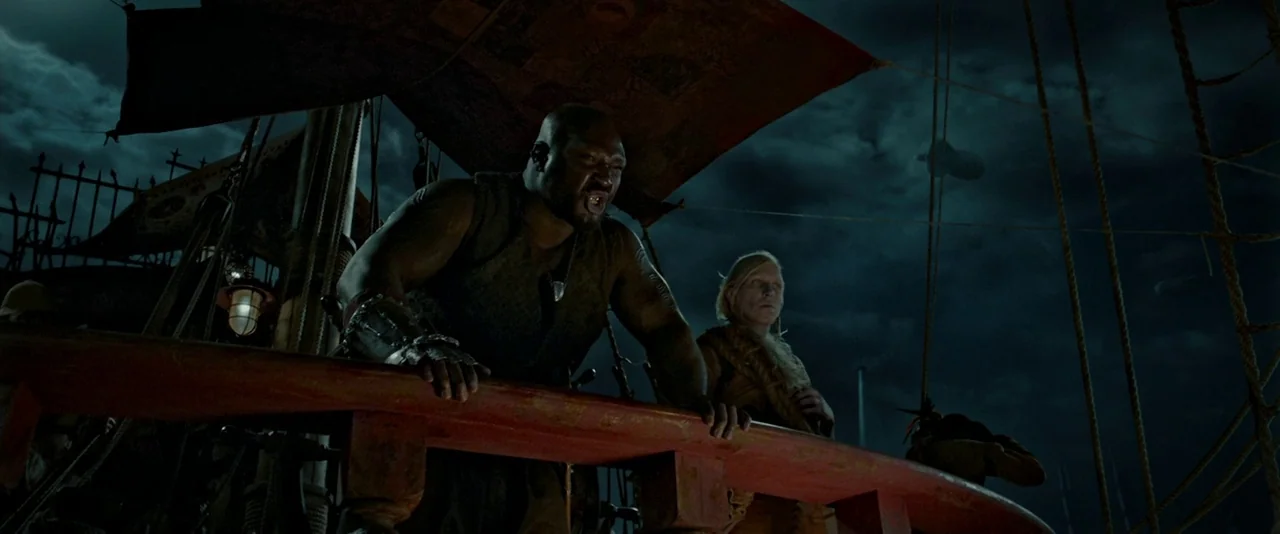 Pan (2015) movie still: medium — The deck of a large sailing vessel at night under dark, cloudy skies. A muscular man shouts while standing at the…