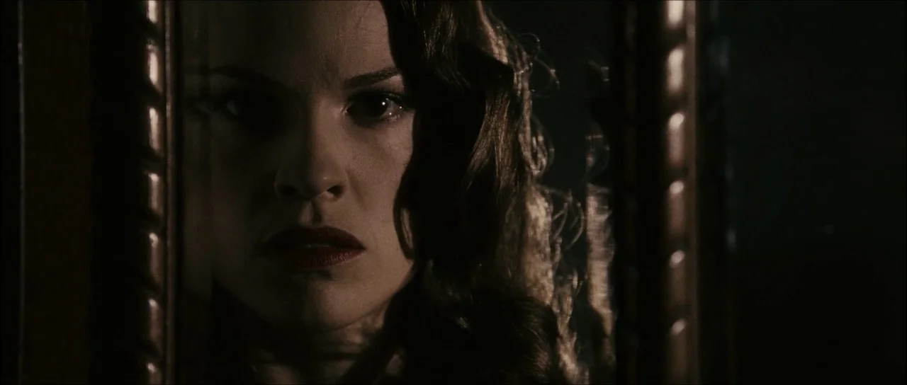 The Black Dahlia (2006) movie still: closeup — A dark space defined by a reflective surface showing a person's reflection. A woman with dark wavy…