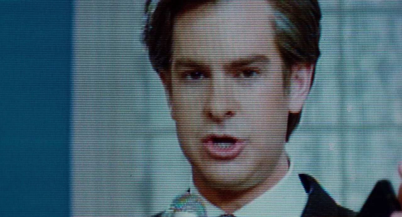 The Eyes of Tammy Faye (2021) movie still: closeup — A man's face fills the frame, captured from a broadcast television source. The subject has an…