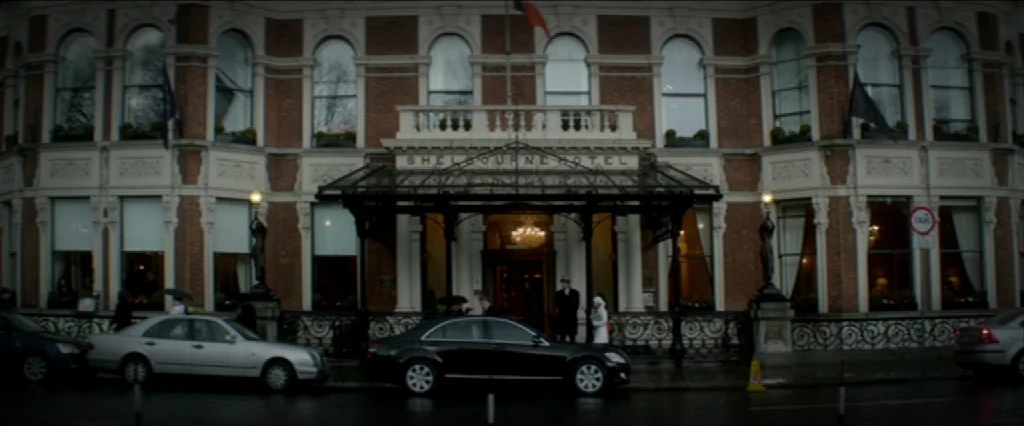 Haywire (2011) movie still: establishing — The brick facade of the historic Shelbourne Hotel displays symmetrical windows and a dark awning. A…