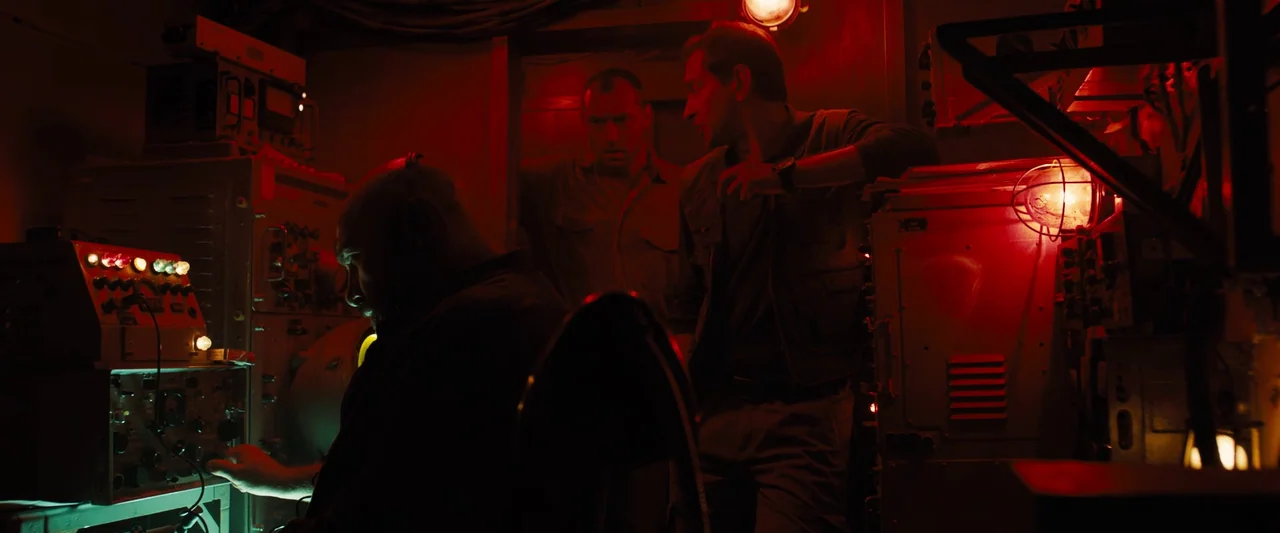 Black Sea (2014) movie still: medium — The interior of a cramped submarine features heavy industrial equipment, dials, and wires throughout. Three…
