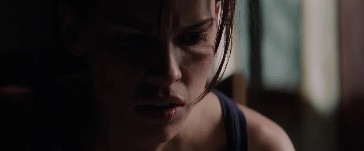 Insomnia (2002) movie still: closeup — An interior space with limited ambient light focused on the subject's face. The woman gazes downward while…