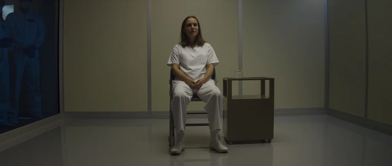 Annihilation (2018) movie still: fullbody — A sterile observation room features light beige paneled walls and a shiny reflective floor. A woman in…