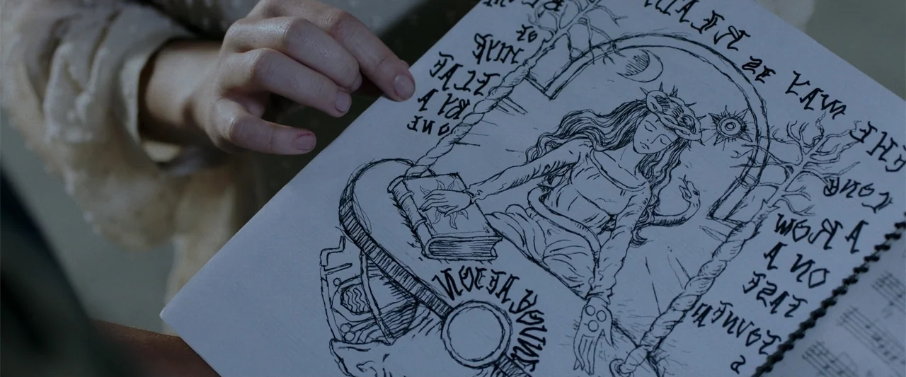 Nocturne (2020) movie still: closeup — An interior space features a person holding a page with detailed ink drawings. The illustration on the paper…
