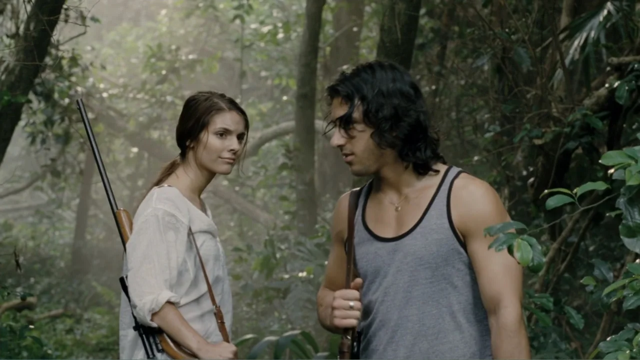 Tomorrow, When the War Began (2010) movie still: medium — A dense green jungle with thick foliage and filtered sunlight through the trees. A man and…