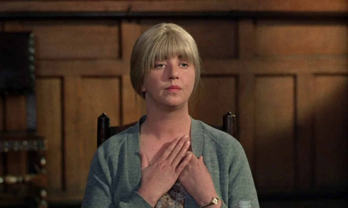 If…. (1968) movie still: medium — An interior space features wood paneling on the wall behind the subject. A woman sits in a wooden chair with her…