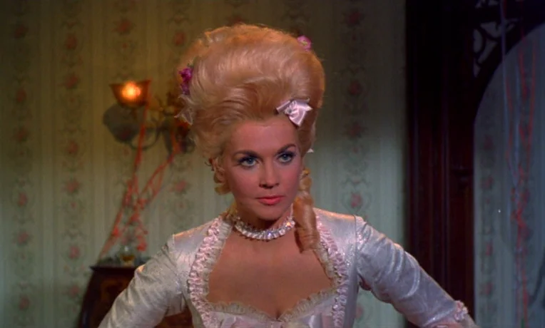 Frankie and Johnny (1966) movie still: medium — An interior space features floral wallpaper and a dark wooden archway. A woman with an elaborate…